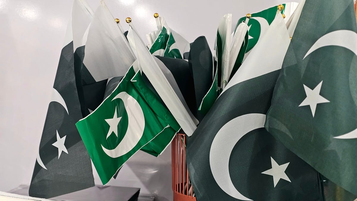 A variety of Pakistani flags grouped together indoors, emphasizing national pride.