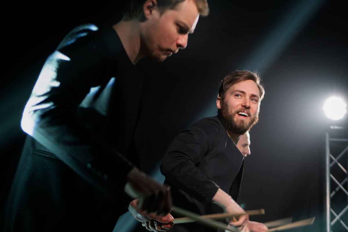 Dynamic drummers performing live on stage with focused lighting.