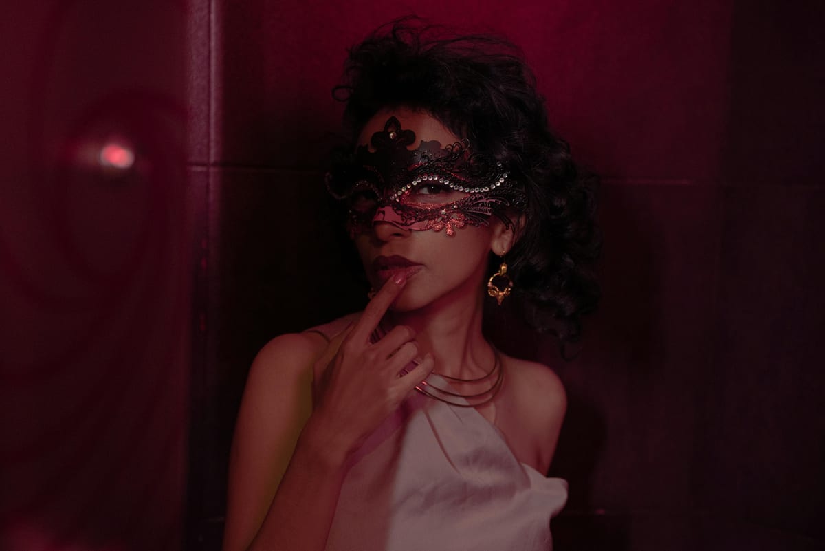 Mysterious woman wearing an ornate mask, exuding elegance and intrigue against a dark background.