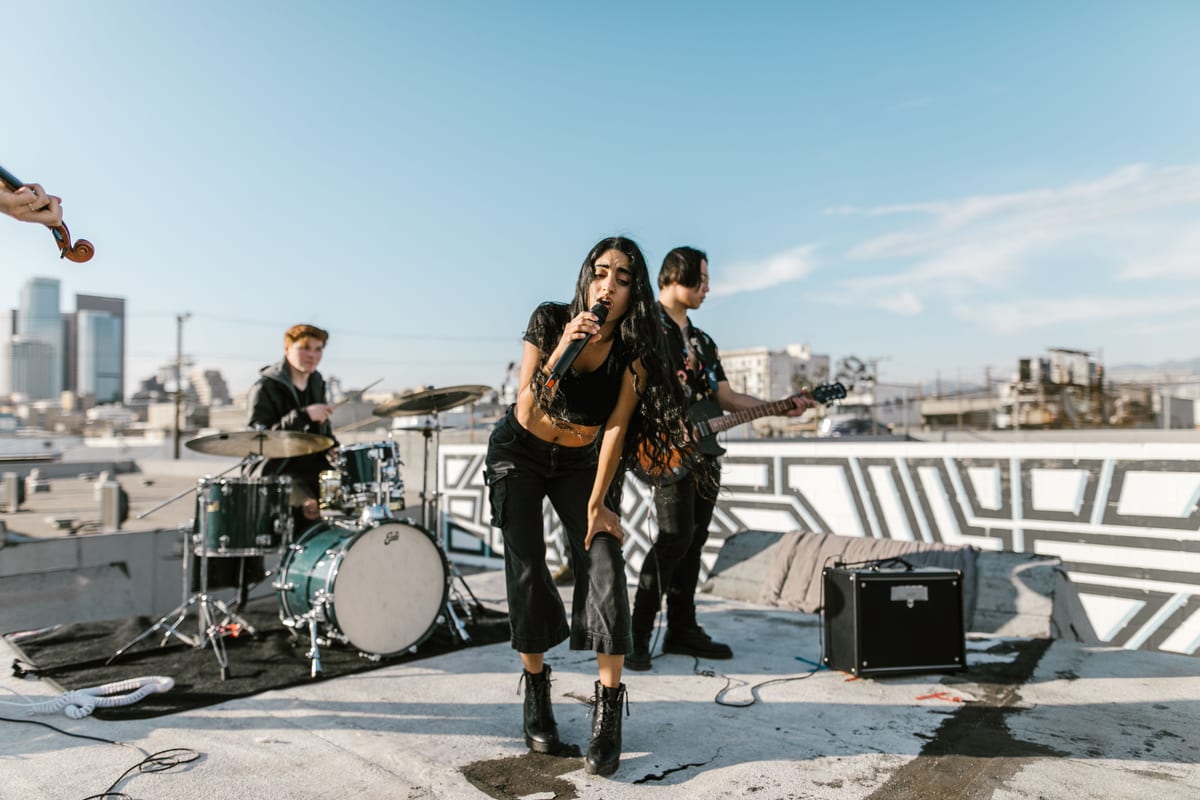 Live outdoor performance by a band on a rooftop with city skyline backdrop.
