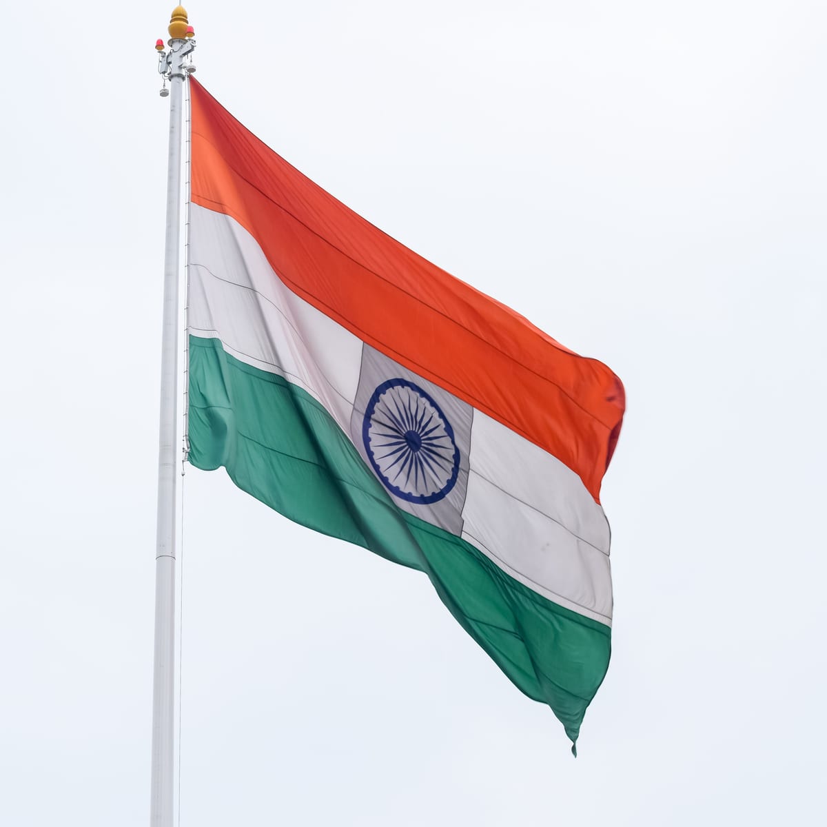 Indian national flag waving against a clear sky symbolizing patriotism and pride.