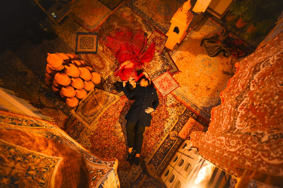 Artistic overhead shot of a couple lying on vibrant rugs in a traditional setting.