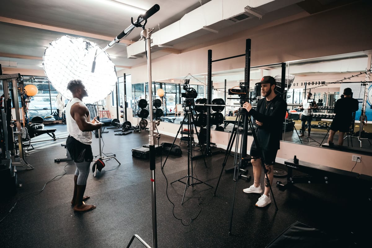 Behind the scenes of a fitness documentary being filmed in a gym with professional lighting equipment.