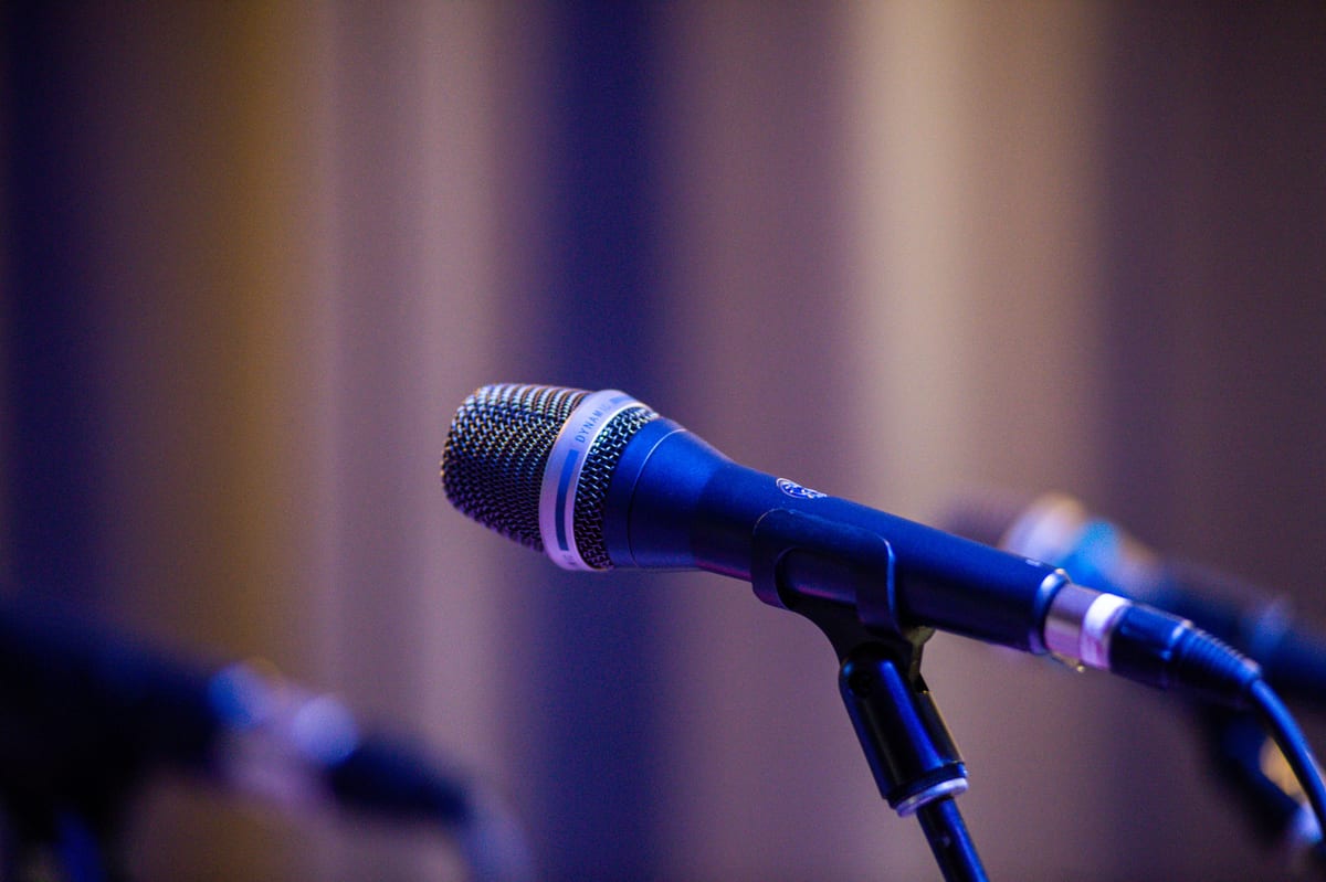 Close-up of a professional microphone on stage with blurred bokeh background.