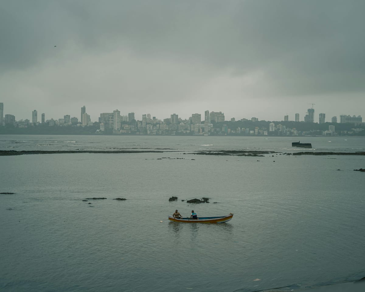 A serene boat ride near Mumbai's skyline on a calm, overcast day, capturing urban and natural beauty.