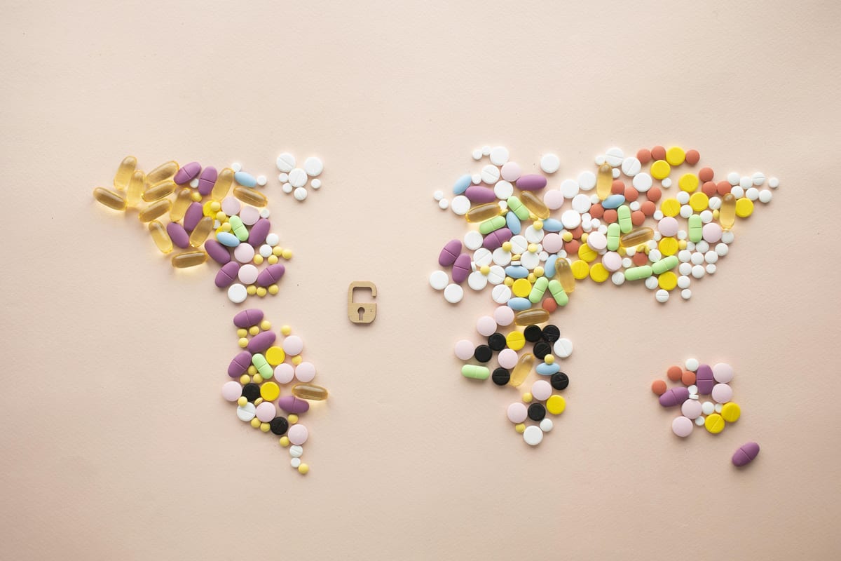 Top view of colorful tablets and capsules arranged on pink background in form of world map near small castle