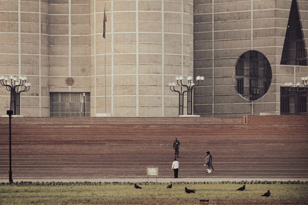 View of the iconic Jatiyo Sangsad Bhaban in Dhaka with people and lawn.