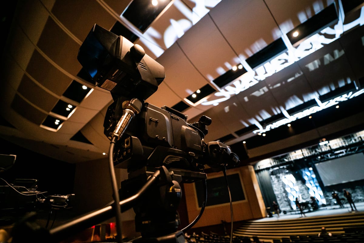 High-quality video camera set up in a modern indoor auditorium for recording or broadcast.