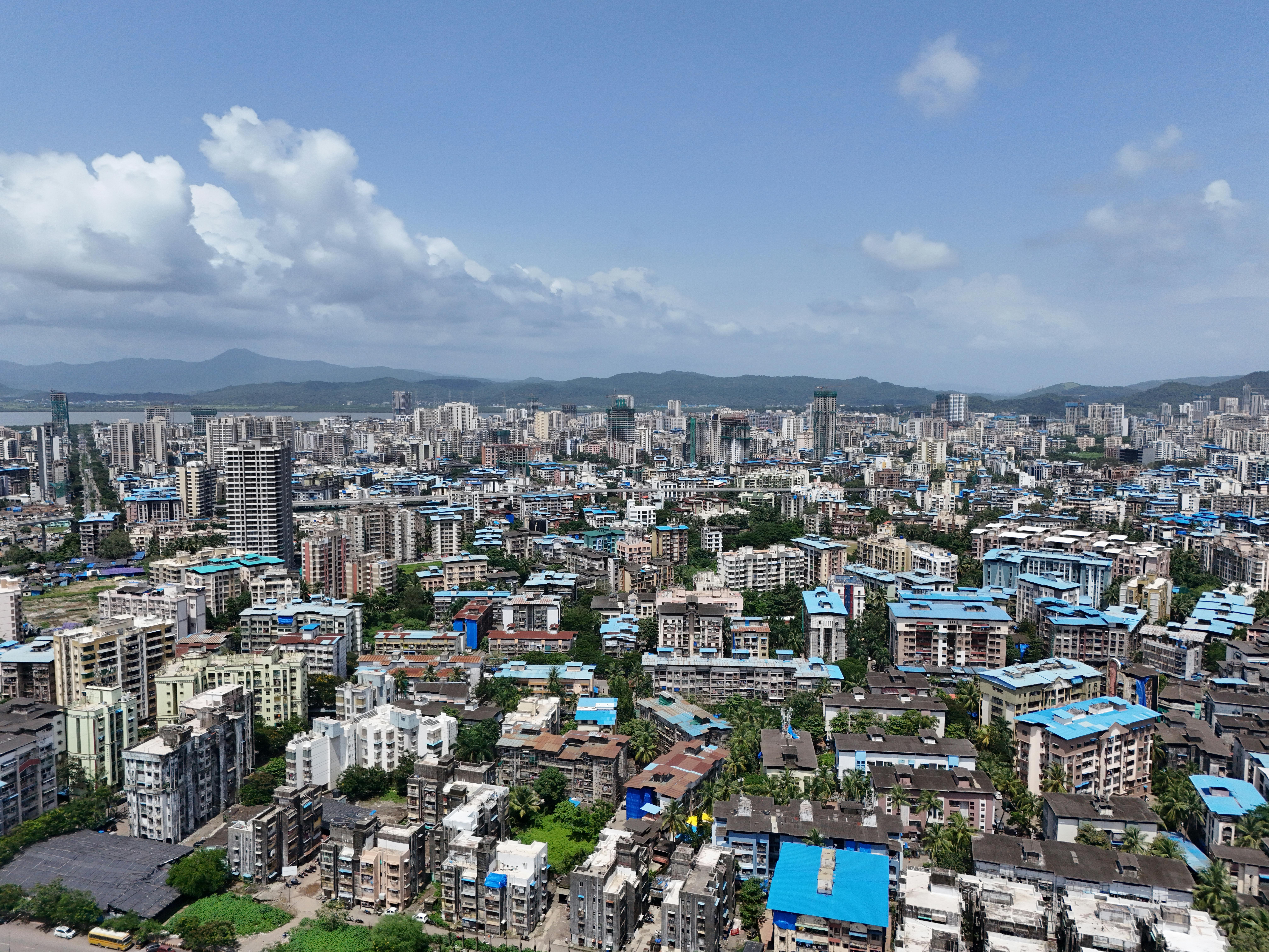 Aerial view of Mumbai showcasing the city's dense skyline under a bright sky.