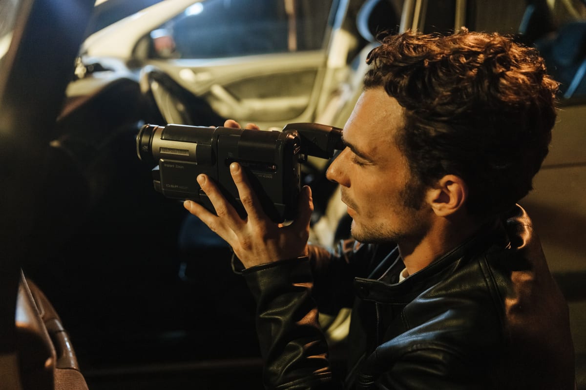 A man uses a camera inside a car during nighttime, possibly capturing footage for an investigation.