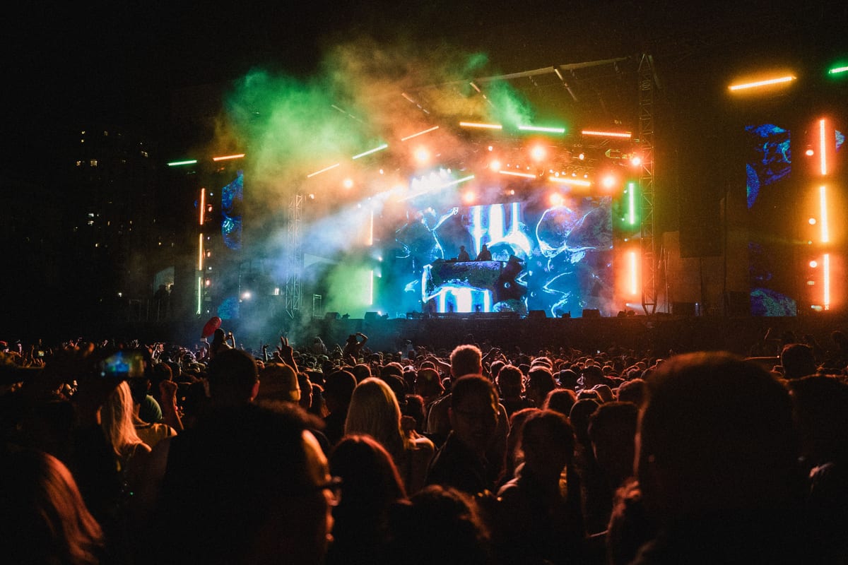 A dynamic and colorful nighttime concert featuring a lively crowd and vibrant stage lights.