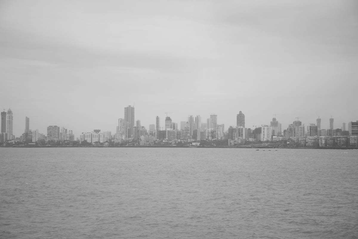 Grayscale view of Mumbai's iconic skyline from the sea, featuring skyscrapers.
