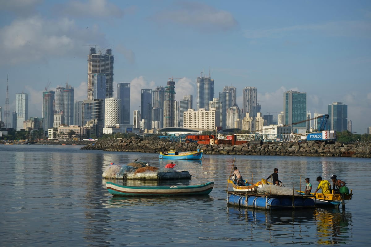 Vibrant view of Mumbai's skyline with local fishing boats on the water, capturing urban and traditional life.