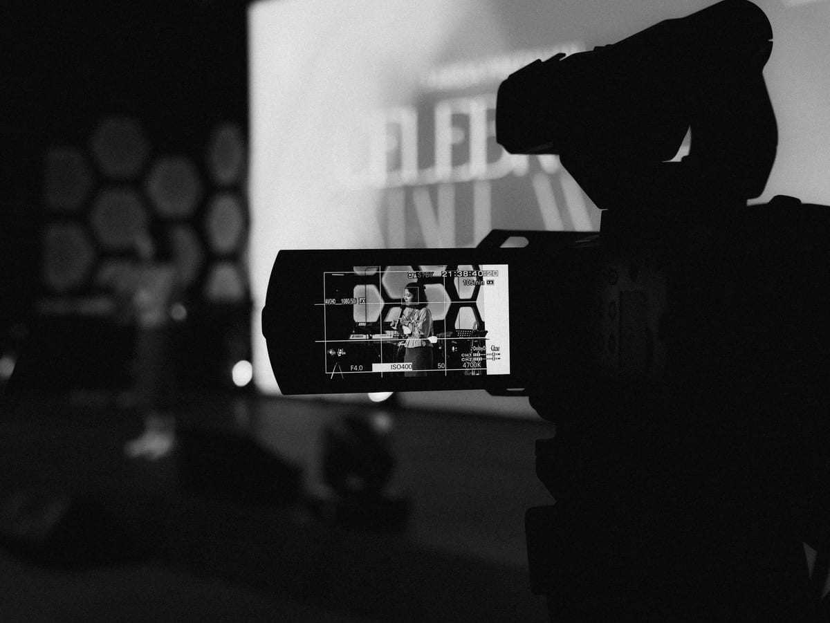 Monochrome image of a video camera capturing a stage event with a blurred background.