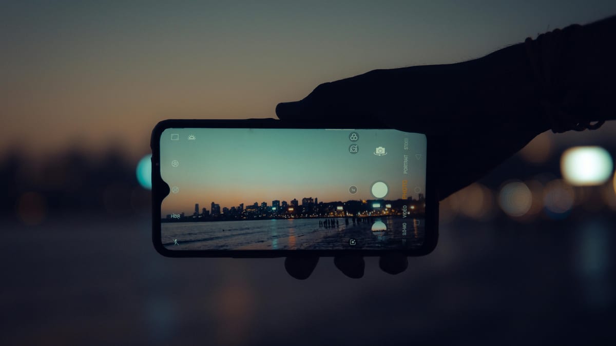 A smartphone capturing the Mumbai skyline at sunset with a clear reflection on its screen.