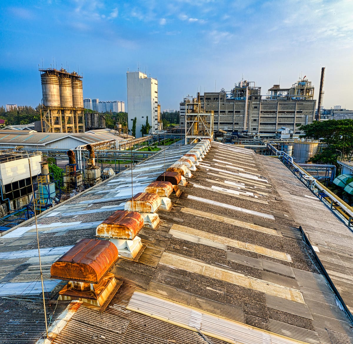 Exterior of aged shabby factory with rusty industrial buildings and mechanisms with pipes in town