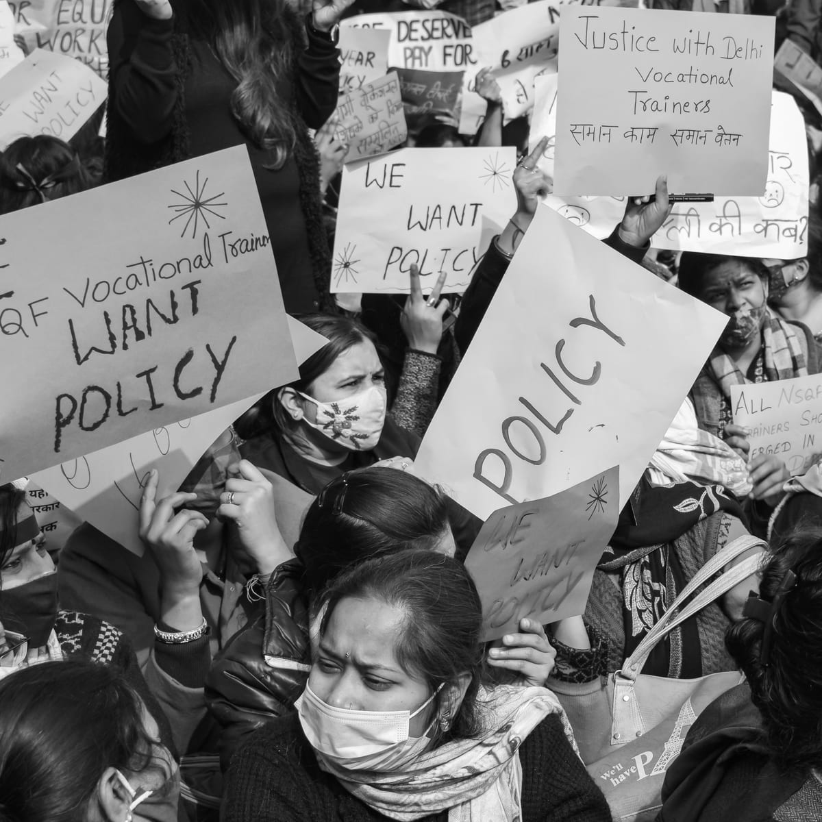 Black and white image of a protest with signs demanding policy changes for vocational trainers.