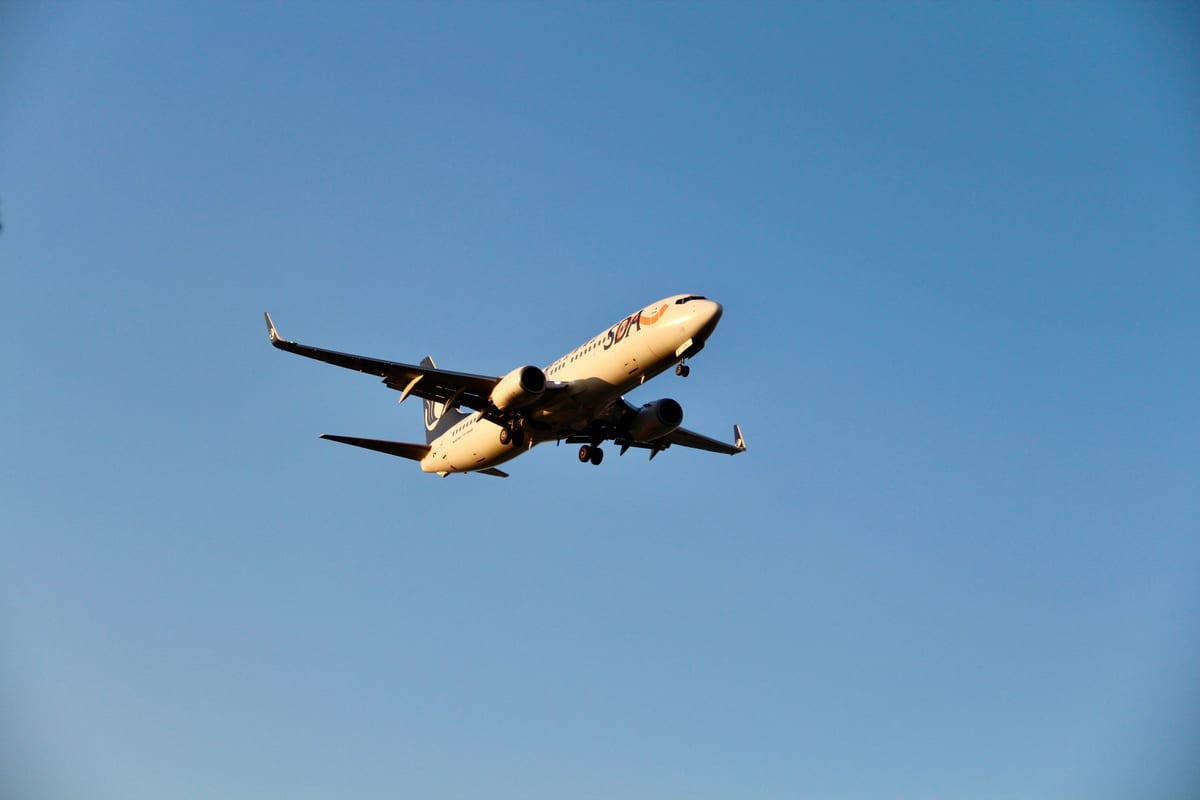 A commercial airplane soars against a bright blue sky, captured in flight.
