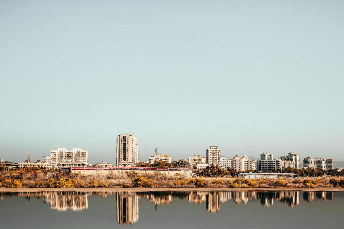 Stunning modern Mumbai skyline reflecting in tranquil waters under a clear sky.