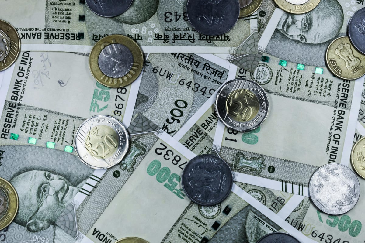 Top view of various Indian rupee banknotes and coins, highlighting financial themes.