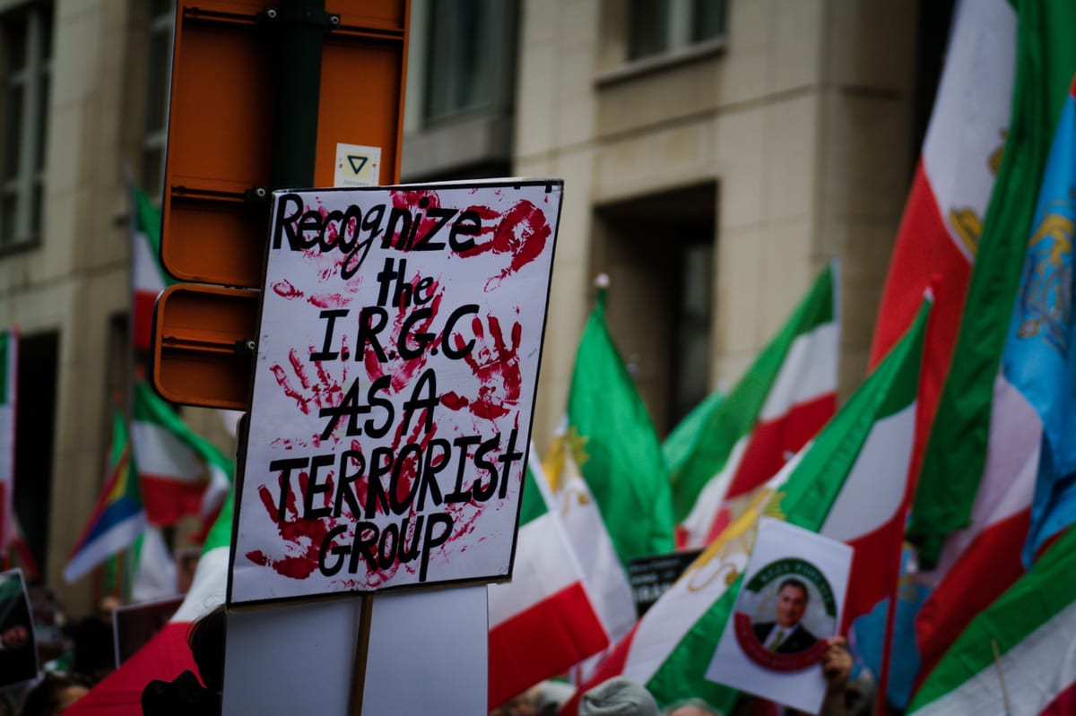 Protest in Brussels with flags and signs demanding IRGC recognition as a terrorist group.