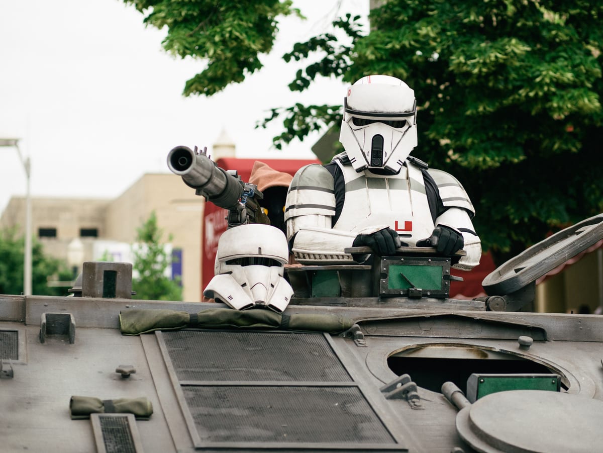 A sci-fi character in armor riding an armored vehicle outdoors.