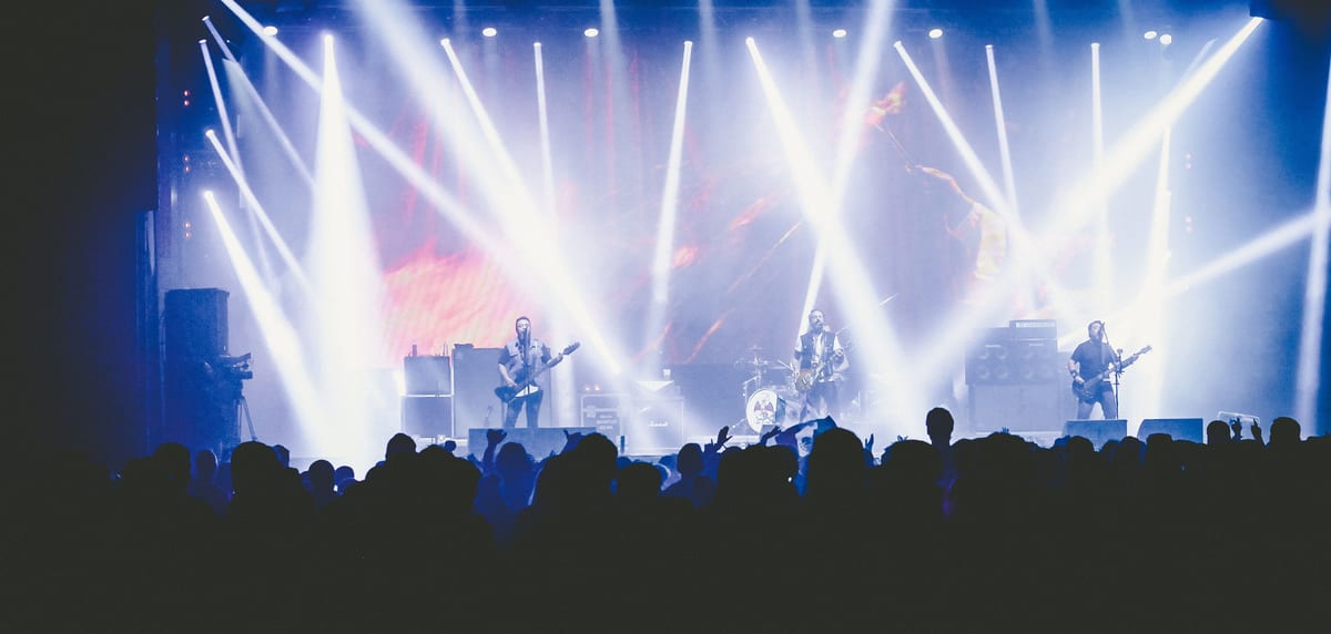 Energetic live concert with a band performing on stage under bright lights.