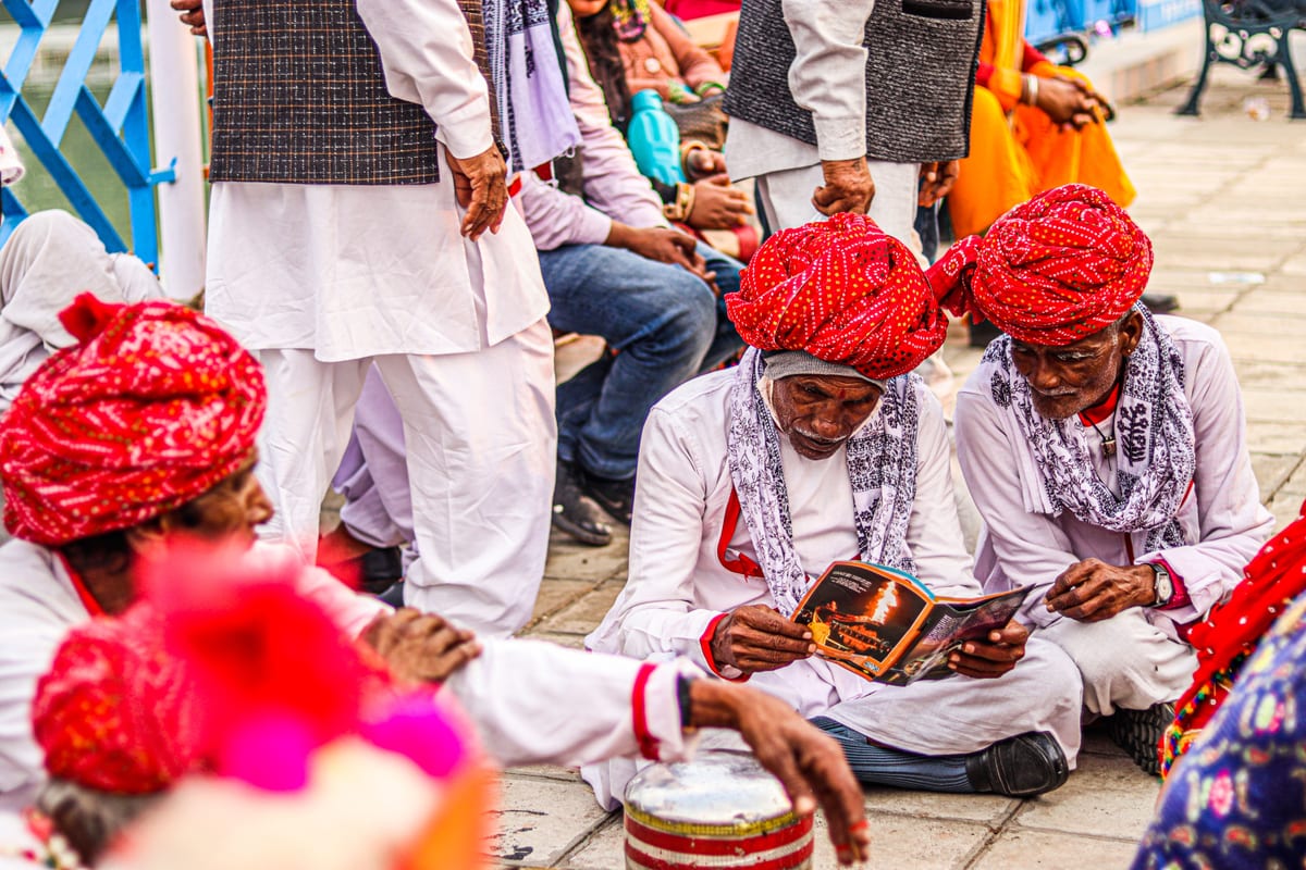 Group of Rajasthani men in traditional turbans engaged in a festive gathering outdoors.