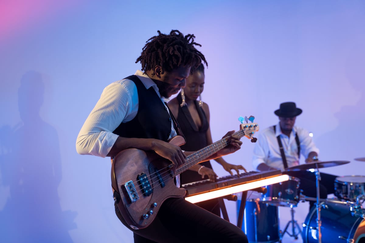 Musicians performing together with guitar, keyboard, and drums under colorful lighting.