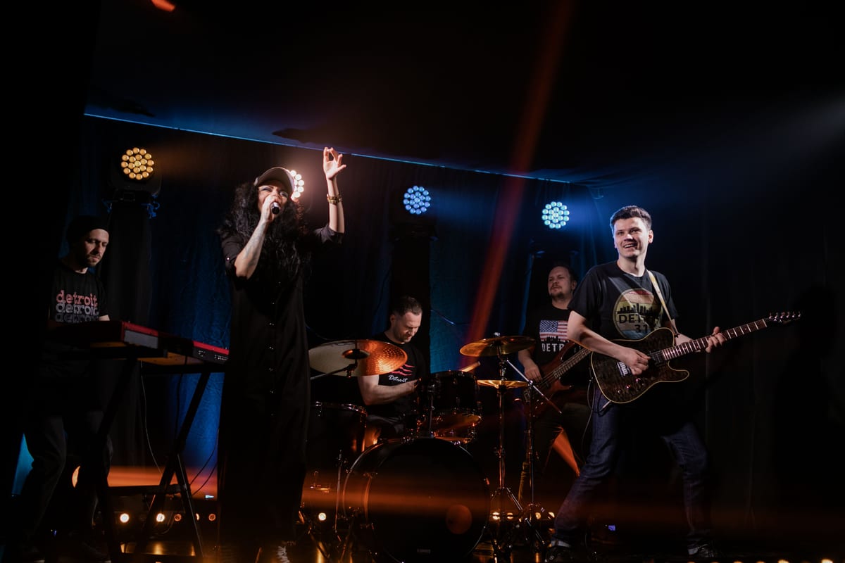 Dynamic live music performance featuring a rock band with singer and instruments on stage.