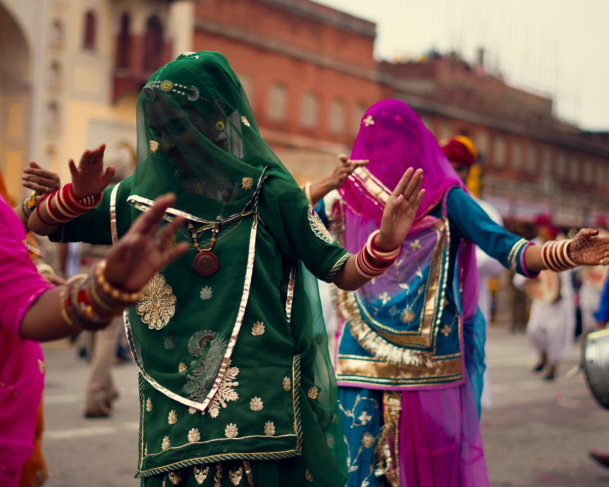 Women in vibrant traditional clothing performing a cultural dance at a street festival.