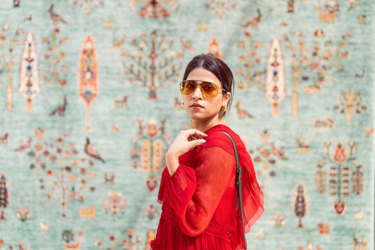 Elegant woman in red dress poses against a decorative wall in Dubai.