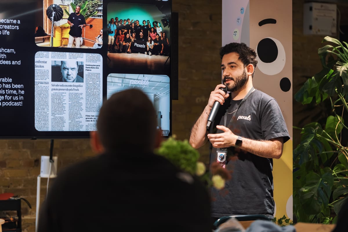 Man presenting with microphone at indoor conference, engaging audience with multimedia display.