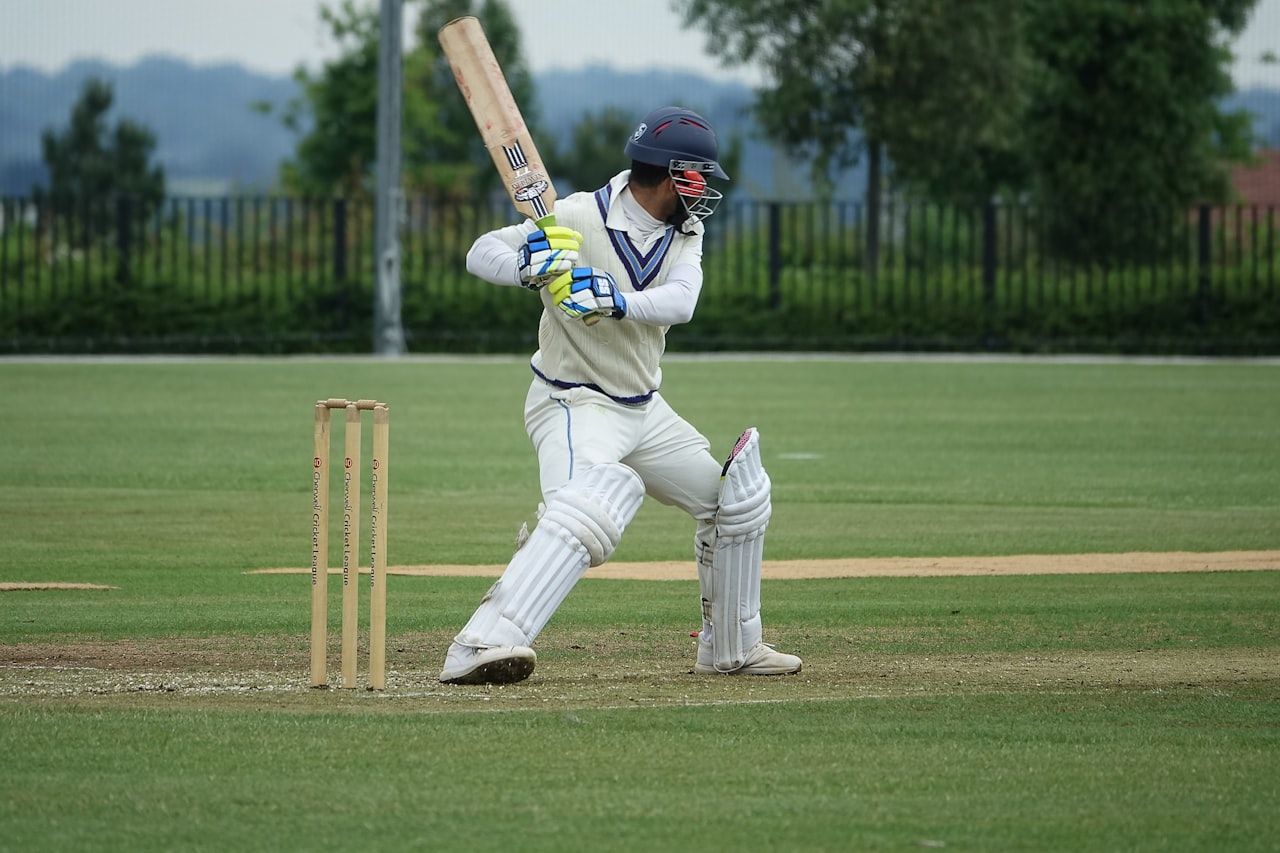 Batsman in traditional whites playing a shot on an English county cricket ground