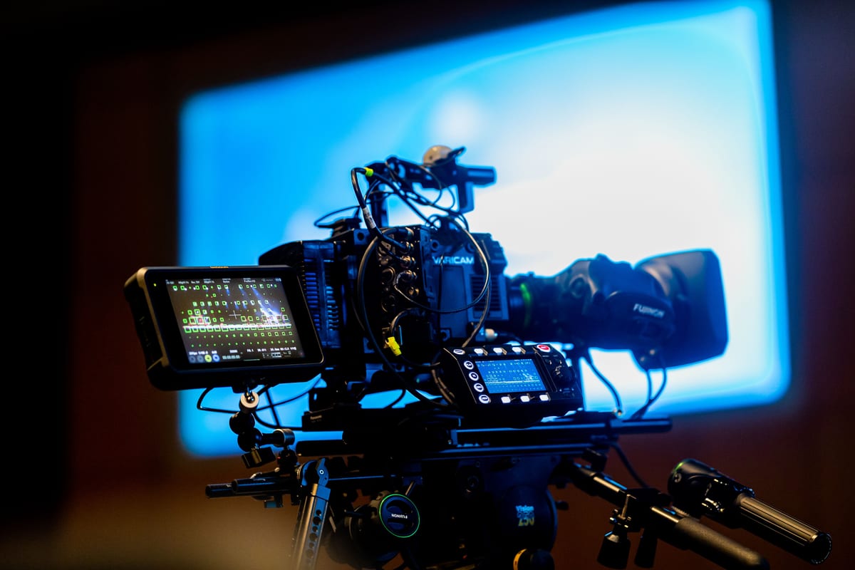 Close-up of a professional video camera setup in a studio environment with vibrant lighting.