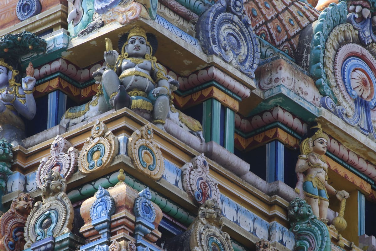 Close-up of detailed ornamentation on a traditional Indian temple, highlighting religious statues and vibrant colors.