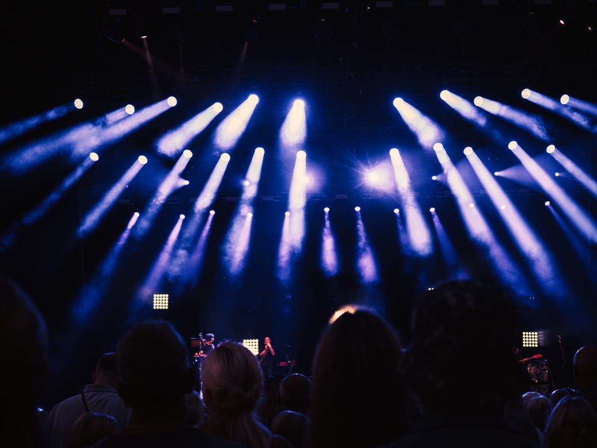 Lively crowd enjoying a concert with stunning stage lights and atmospheric ambiance.