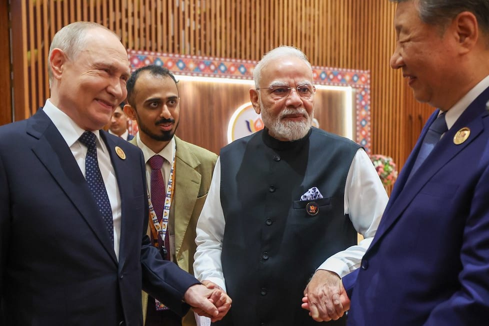 Prime Minister Narendra Modi stands between President Vladimir Putin and President Xi Jinping, holding both their hands, at the 18th BRICS Summit, Bharat Mandapam, New Delhi