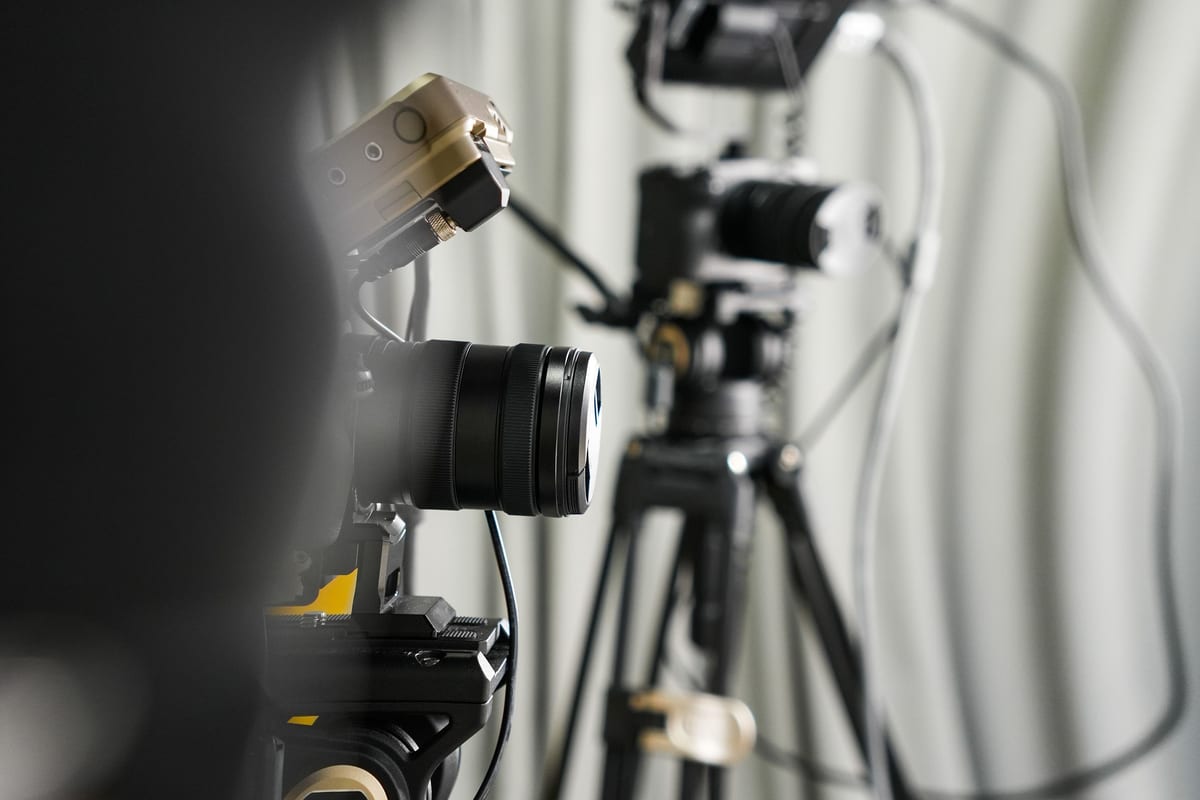 Close-up of professional video cameras on tripods in a studio setting.