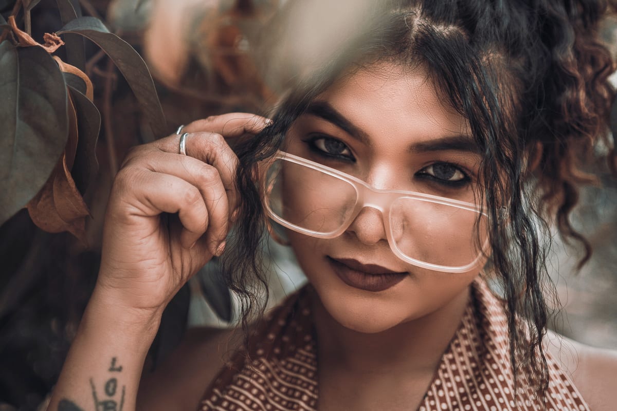 Close-up portrait of a woman with glasses and curly hair, showcasing personal style.