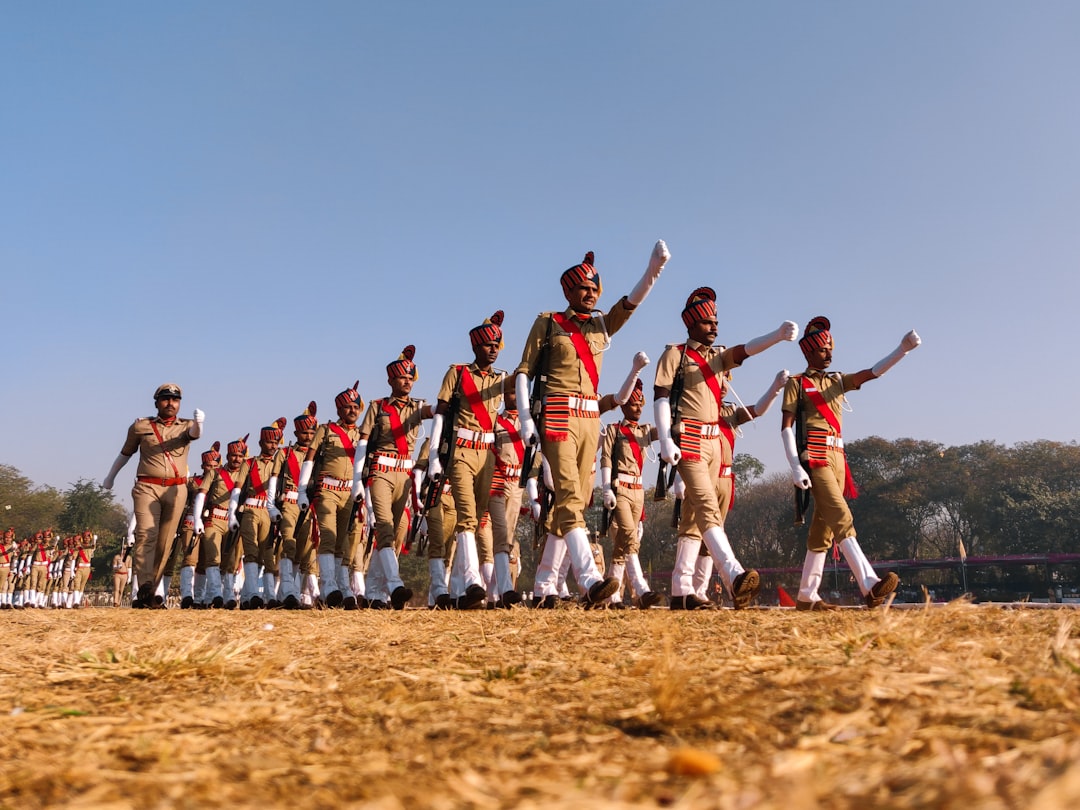 group of people in red and white shirts and pants jumping on brown field during daytime