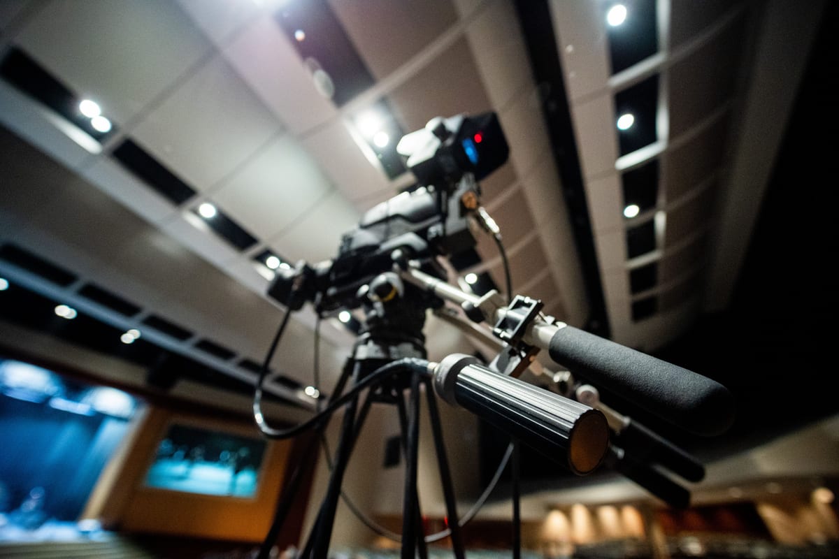 From below of modern professional video camera with wires placed on tripod in studio on blurred background