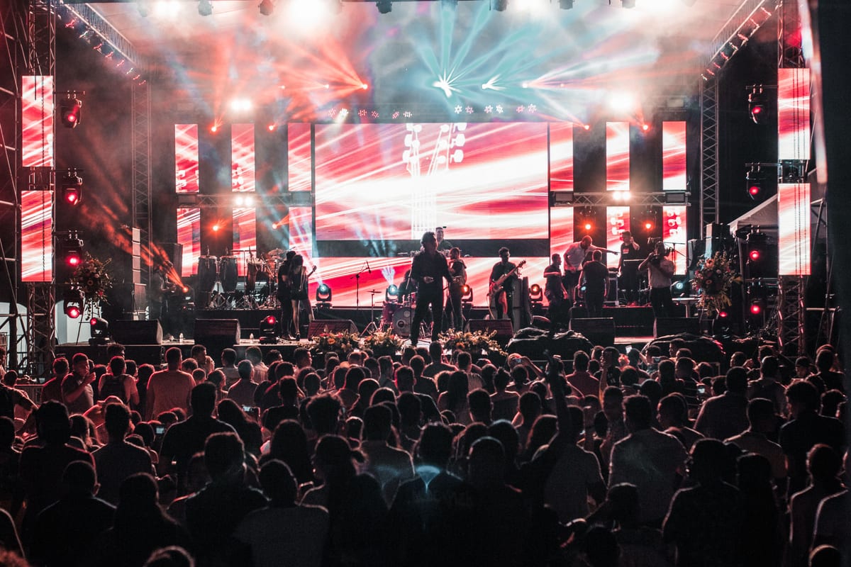 Vibrant outdoor concert event in Santa Marta with a lively crowd and colorful lighting effects.