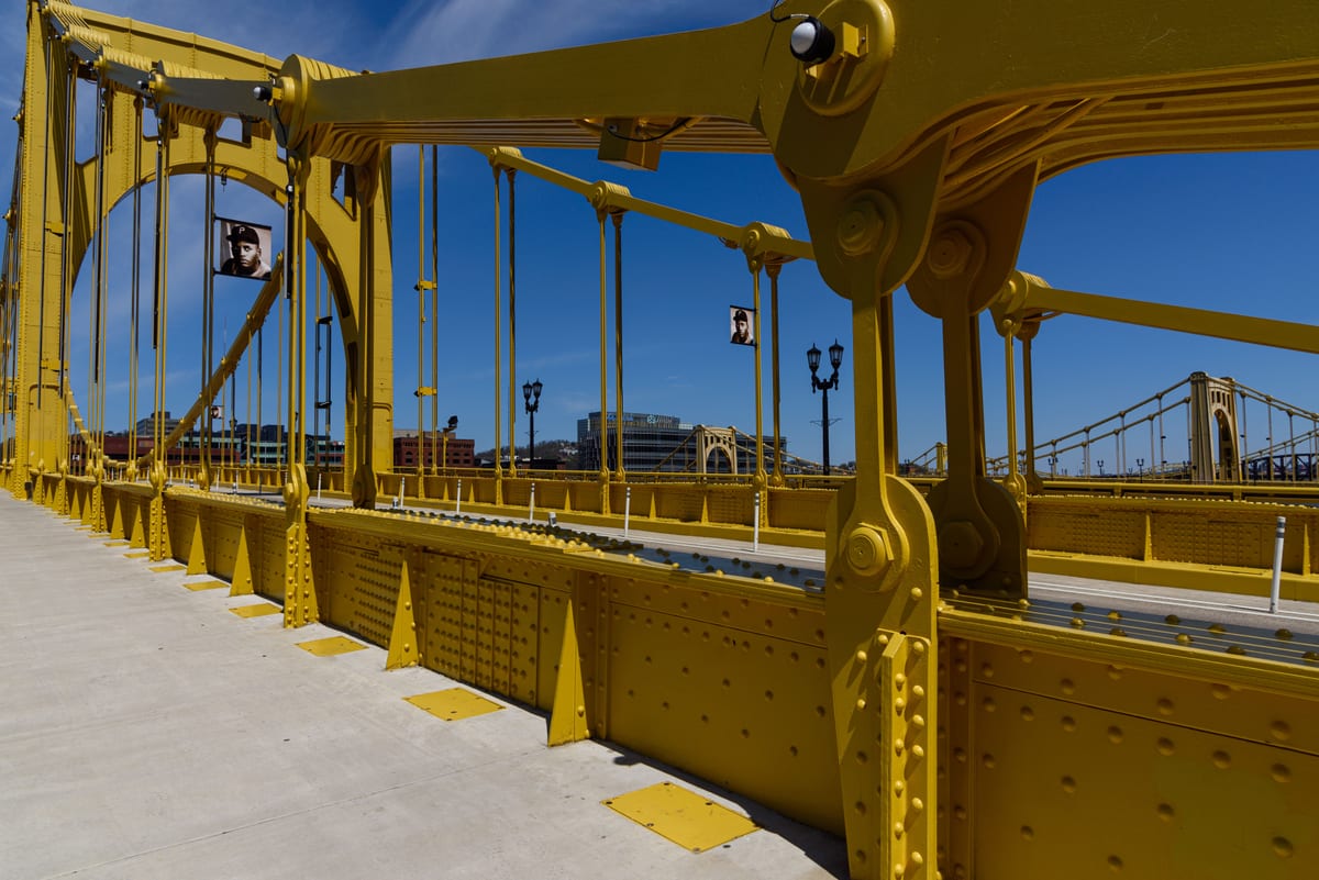 Vibrant yellow suspension bridge standing out against a clear blue sky, showcasing modern engineering.
