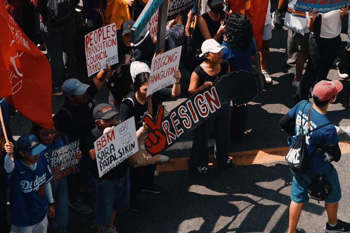 People rallying in urban protest with signs calling for political change.