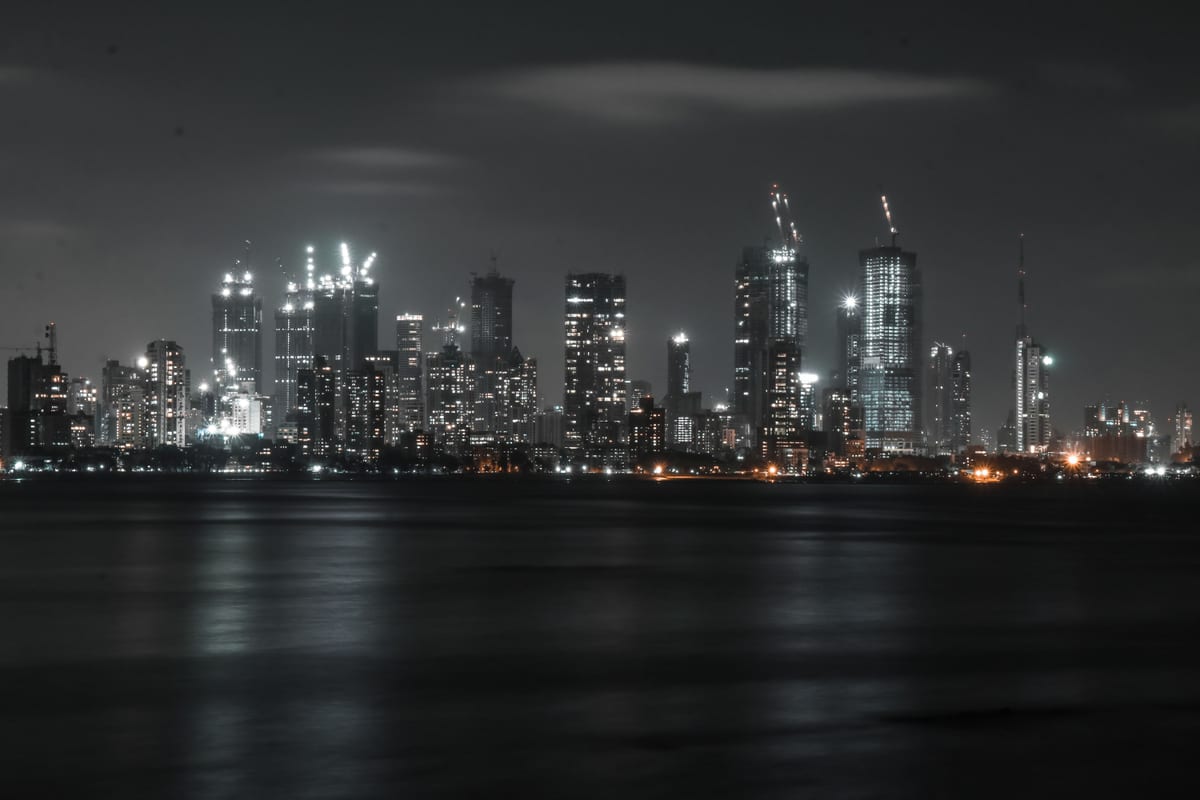 An impressive city skyline illuminated at night, reflected on water.