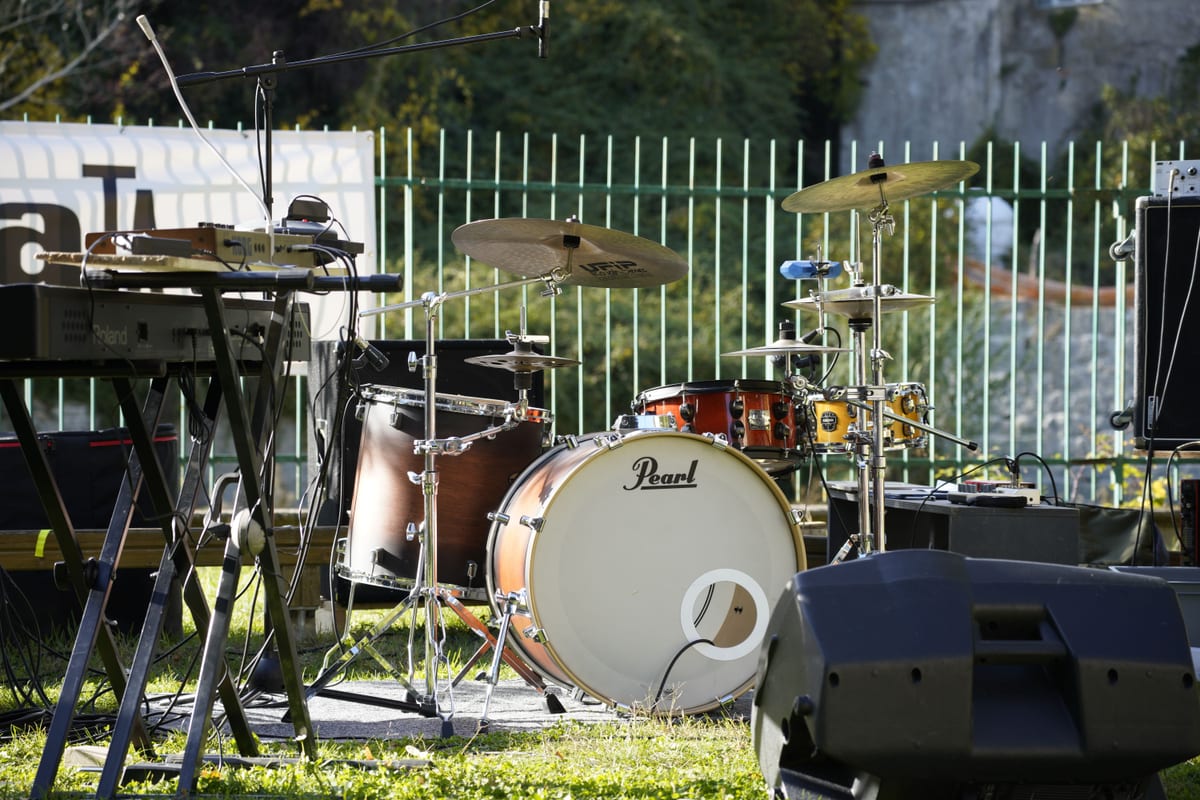 An outdoor music stage setup featuring a drum set and keyboard, ready for a live performance.