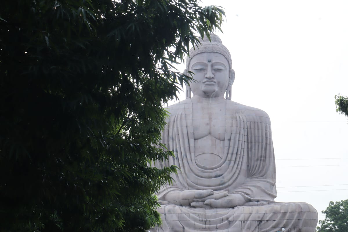 Majestic Great Buddha statue surrounded by green foliage in Bodh Gaya, India.