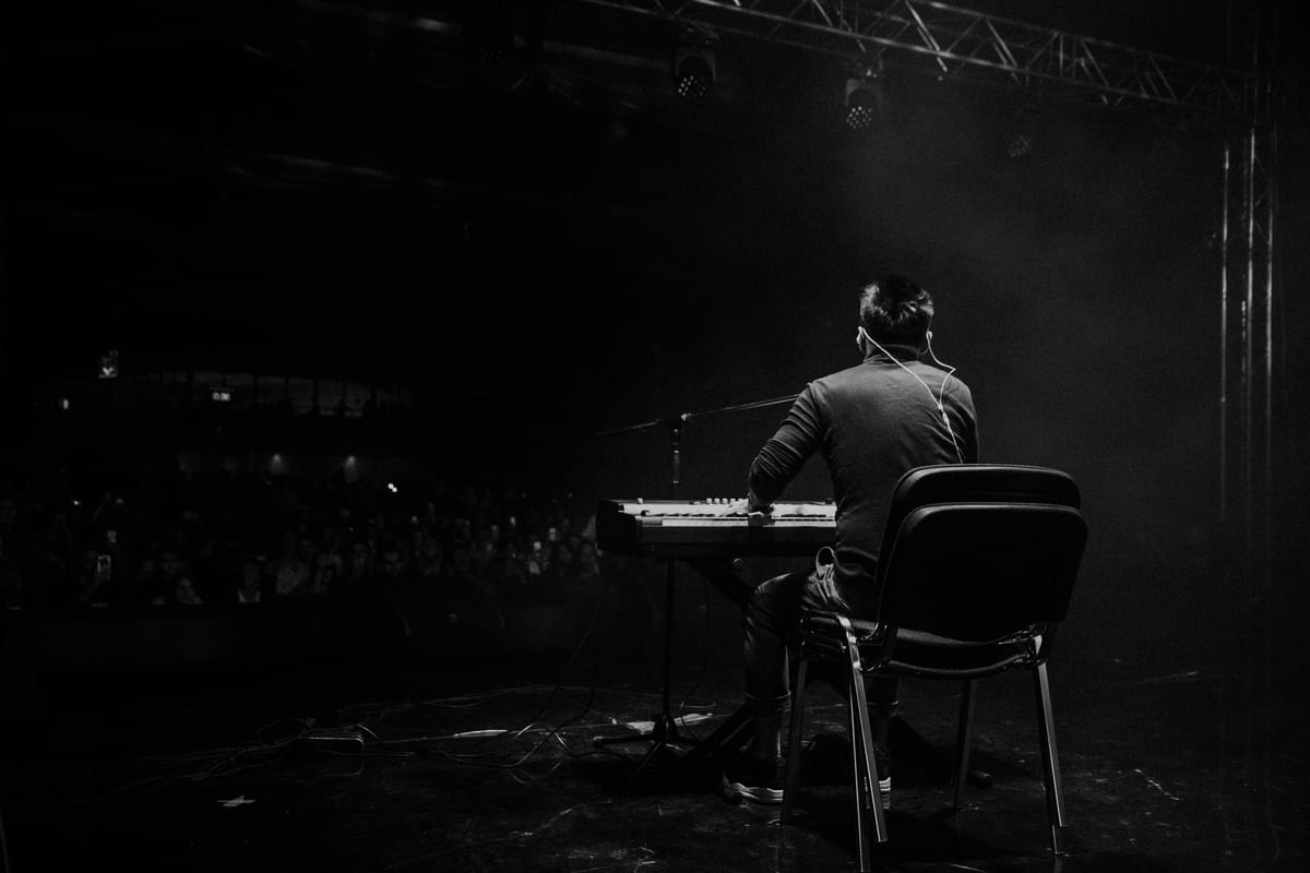 A musician playing piano on stage at a live concert. Captivating atmosphere.