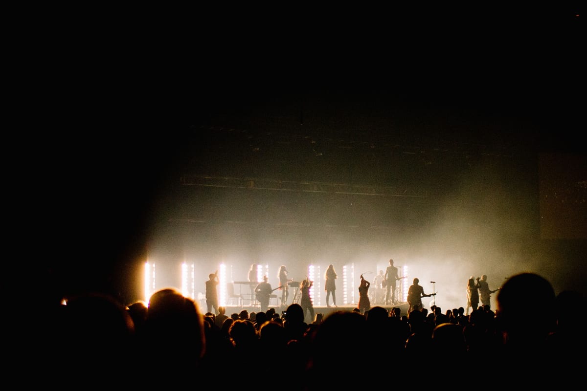 Silhouetted performers energize a concert crowd with dramatic stage lighting.
